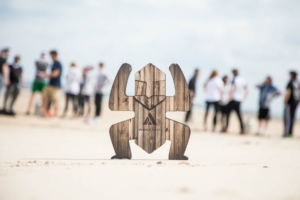 totem du Robinson’s Quest planté sur la plage avec participants en arrière plan