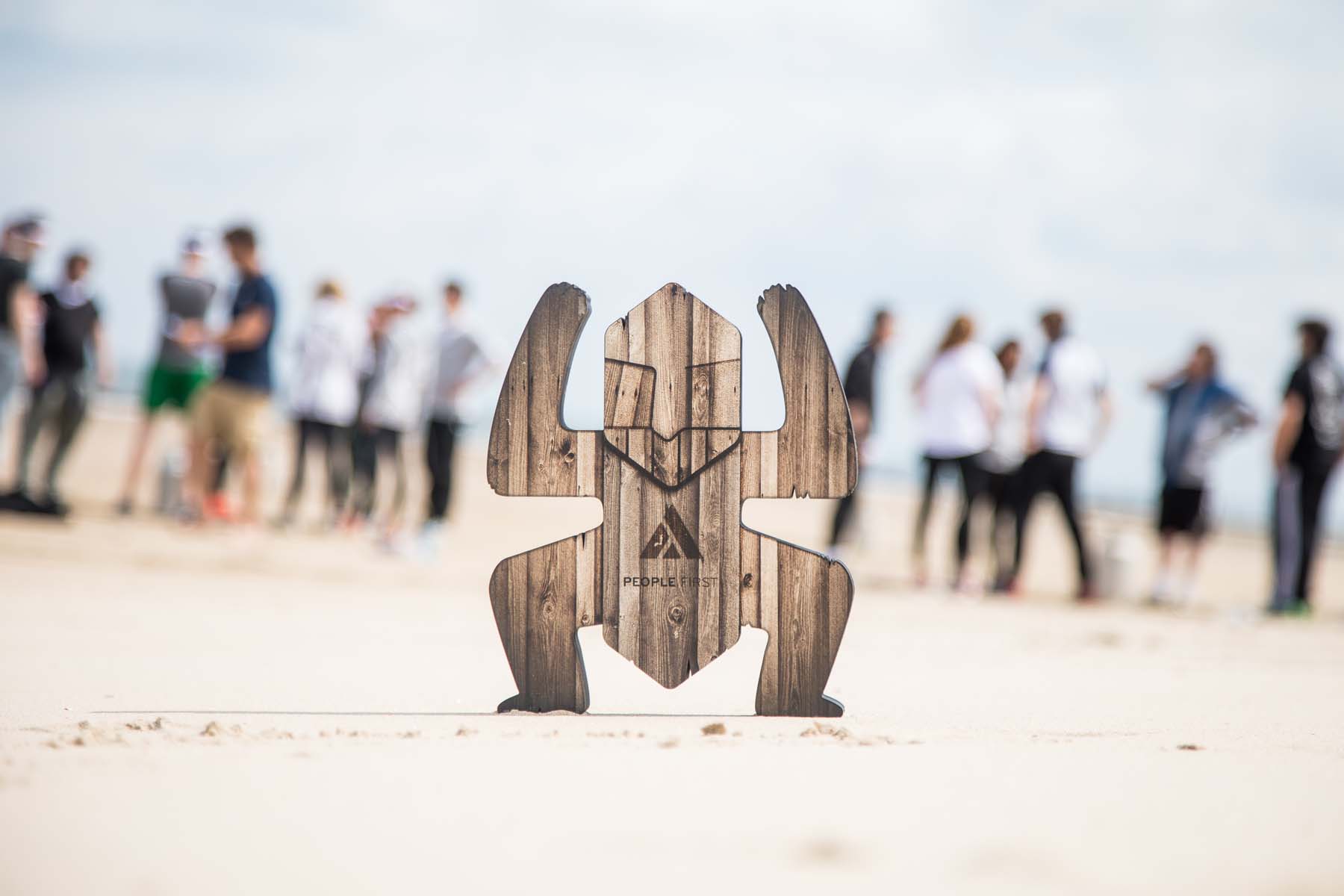 Robinson's Quest totem pole planted on the beach with participants in the background