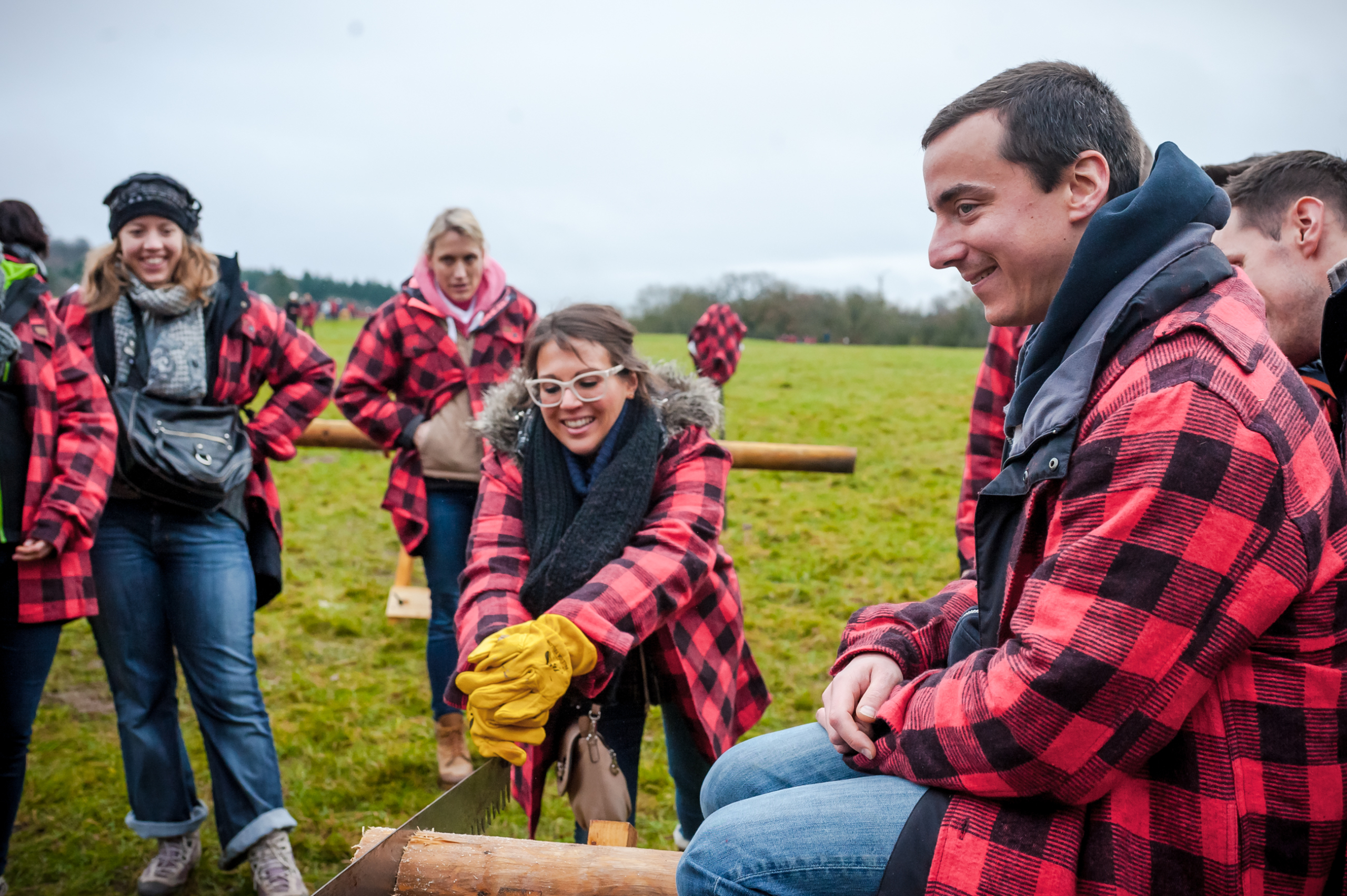 participant sawing a log with the help of her team during the Forest Games