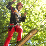 participants advancing/climbing on a rock face during an aerial course