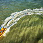 aerial view of the sea where a boat is pulling a board during the Beach & Water Olympics