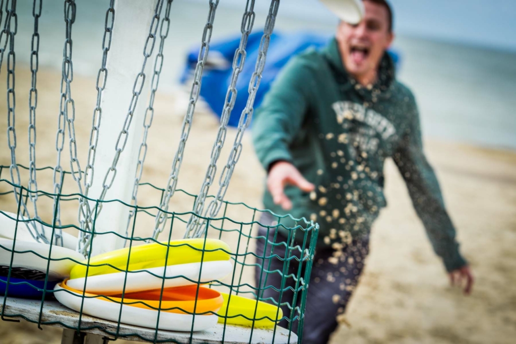 participant throwing a frisbee in the basket during the Beach Olympics