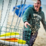 participant throwing a frisbee in the basket during the Beach Olympics