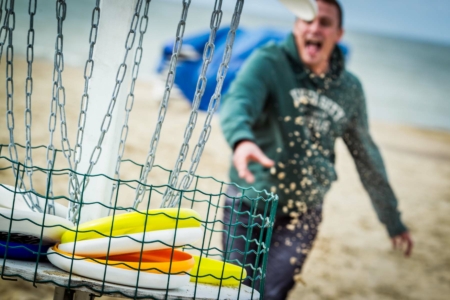 participant lançant un frisbee dans le panier lors du Beach Olympics