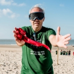 participants blindfolded and with open arms during the Beach Olympics